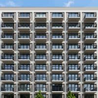 A small project thumbnail of an apartment complex facade with rows of repeating balconies rising against a clear sky.
