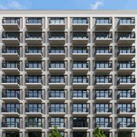 A small project thumbnail of an apartment complex facade with rows of repeating balconies rising against a clear sky.